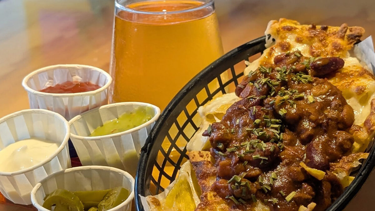 Loaded nachos and a pint of beer on a table at Meeple Play Cafe, Hythe — Friday and Saturday bar food near you