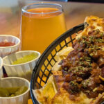 Loaded nachos and a pint of beer on a table at Meeple Play Cafe, Hythe — Friday and Saturday bar food near you
