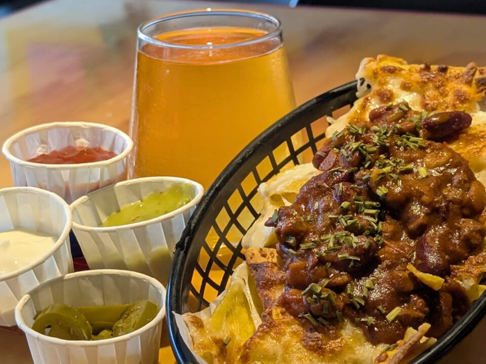 Loaded nachos and a pint of beer on a table at Meeple Play Cafe, Hythe — Friday and Saturday bar food near you