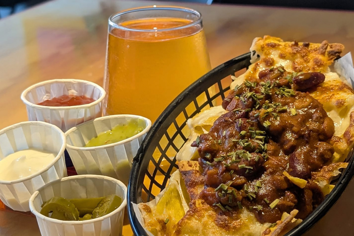 Loaded nachos and a pint of beer on a table at Meeple Play Cafe, Hythe — Friday and Saturday bar food near you